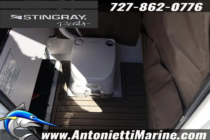 Slide: The Image of 2026 Stingray 216 CC boat interior with portable toilet, featuring marine flooring. - 38