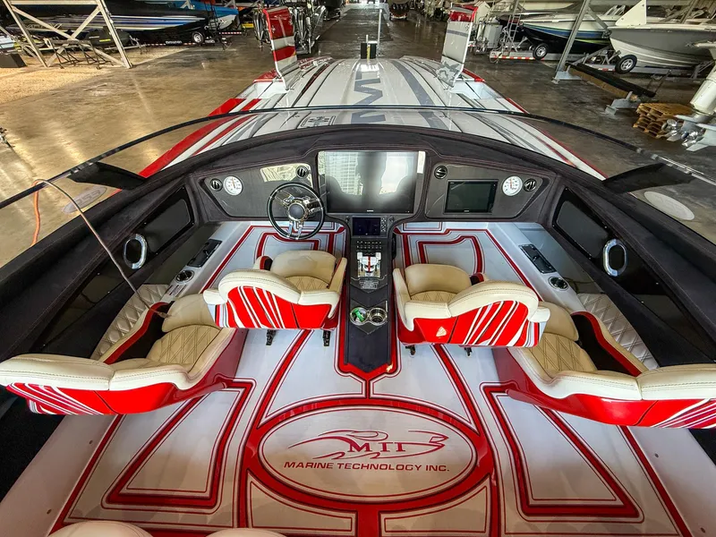 Slide: The Image of Interior of 2019 MTI 48 boat with red and white seating and advanced dashboard controls. - 25