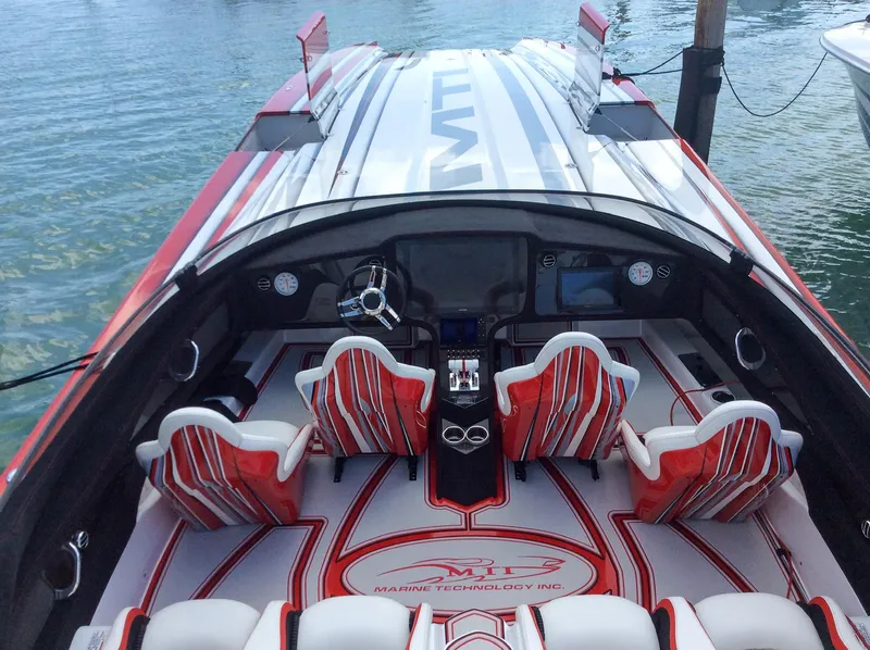 Slide: The Image of 2019 MTI 48 speedboat interior with red and white seating, sleek dashboard, and water backdrop. - 7