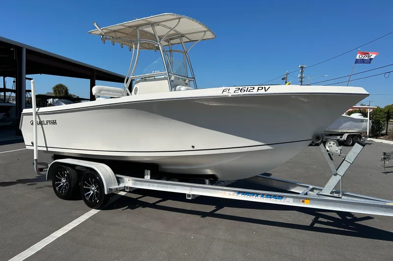 The Image of 2015 Sailfish 220 CC boat on trailer, parked outdoors under clear blue sky. - 1