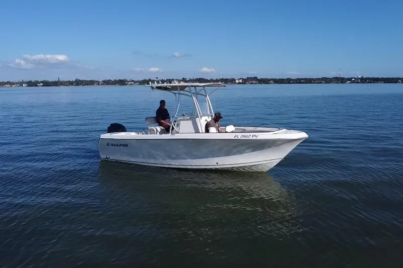 Slide: The Image of 2015 Sailfish 220 CC boat on calm water with two people aboard. - 19
