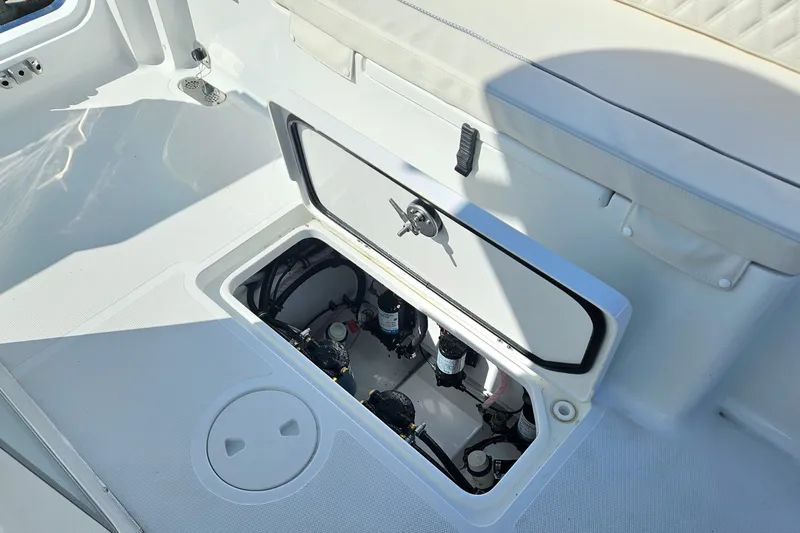 Slide: The Image of 2026 Sea Hunt Ultra 285 SE boat storage compartment with open hatch, revealing internal components. - 14