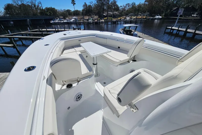 Slide: The Image of 2026 Sea Hunt Ultra 285 SE boat interior with white seating and table, docked by the water. - 26