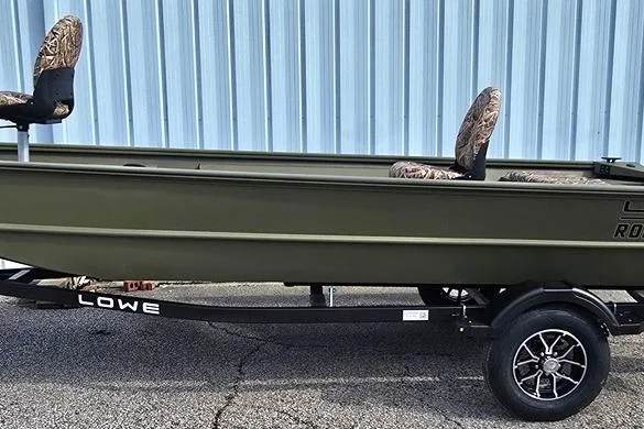 Slide: The Image of 2026 Lowe Roughneck RX1860 Tiller boat on trailer, camo seats, blue metal wall background. - 5