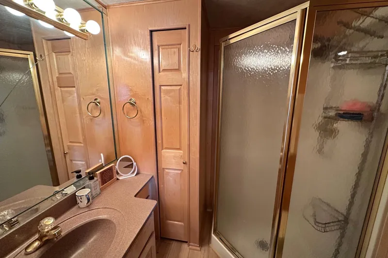 Slide: The Image of Bathroom in 2000 Sumerset 16x73 houseboat with wooden cabinets and glass shower. - 12