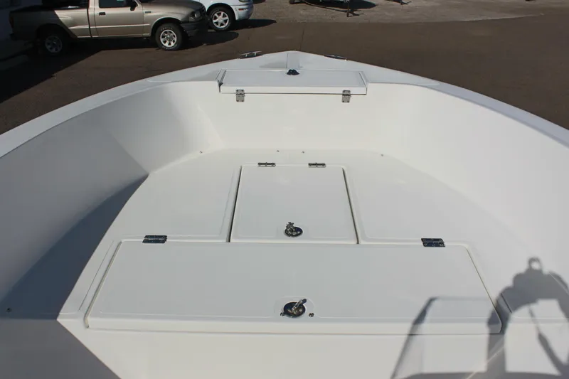 Slide: The Image of 2024 Clear Water 2000 CC boat deck with storage compartments, parked near vehicles. - 14