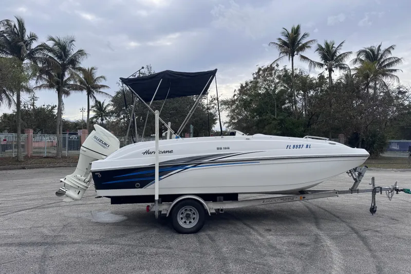 Slide: The Image of 2018 Hurricane SunDeck Sport 188 OB boat on trailer, parked with palm trees in background. - 15