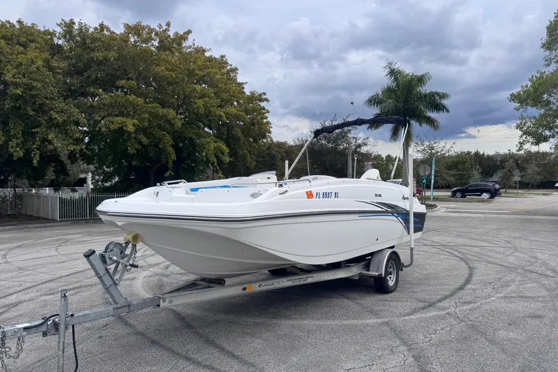Slide: The Image of 2018 Hurricane SunDeck Sport 188 OB boat on trailer, parked in a lot with trees. - 8