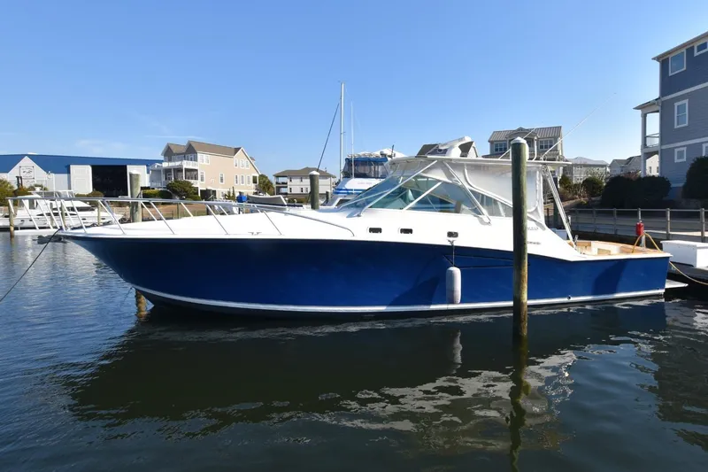 The Image of 1998 Cabo 45 Express boat docked in a marina, featuring a sleek blue and white design. - 0