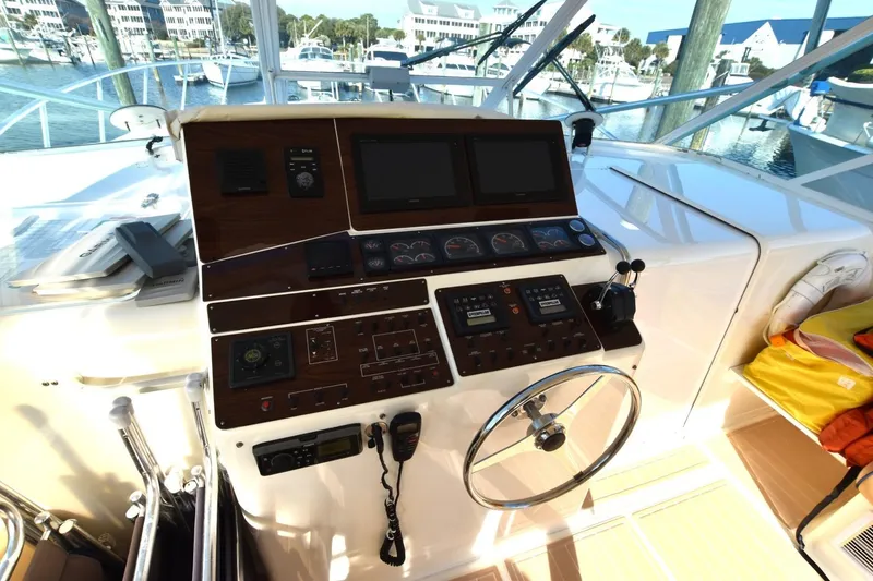 Slide: The Image of 1998 Cabo 45 Express yacht helm with navigation controls and steering wheel. - 9