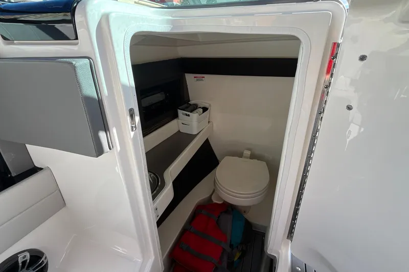 Slide: The Image of 2021 Sea Ray SLX 280 boat interior with compact bathroom and storage space. - 20