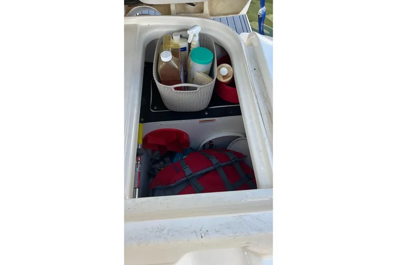 Slide: The Image of Storage compartment in 2021 Sea Ray SLX 280 boat with cleaning supplies and life jacket. - 67