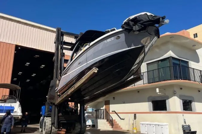 Slide: The Image of 2021 Sea Ray SLX 280 boat lifted by forklift outside storage facility. - 69