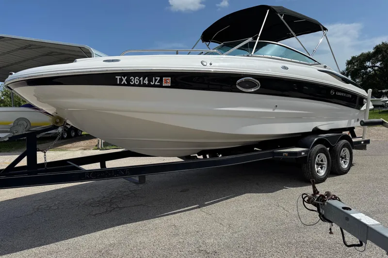 The Image of 2004 Crownline 248 BR boat on trailer with canopy, parked outdoors. - 1