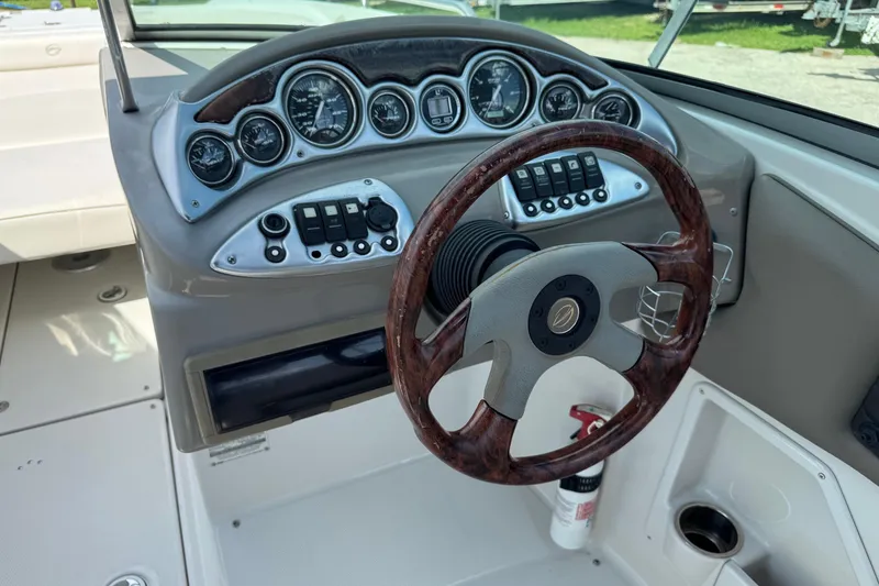 Slide: The Image of 2004 Crownline 248 BR boat dashboard with wood-accented steering wheel and instrument panel. - 18