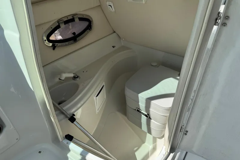 Slide: The Image of 2004 Crownline 248 BR boat interior with compact bathroom and porthole window. - 20