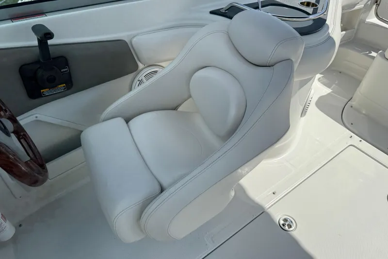 Slide: The Image of 2004 Crownline 248 BR boat interior with plush white captain's chair and steering wheel. - 22