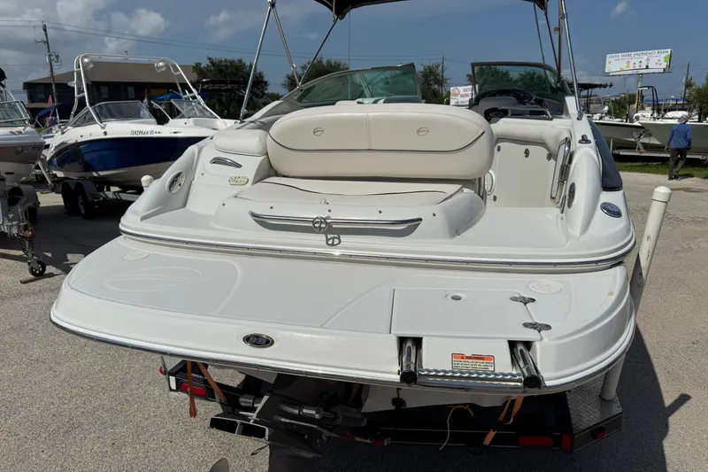 Slide: The Image of 2004 Crownline 248 BR boat, rear view, white exterior, parked on a trailer. - 7