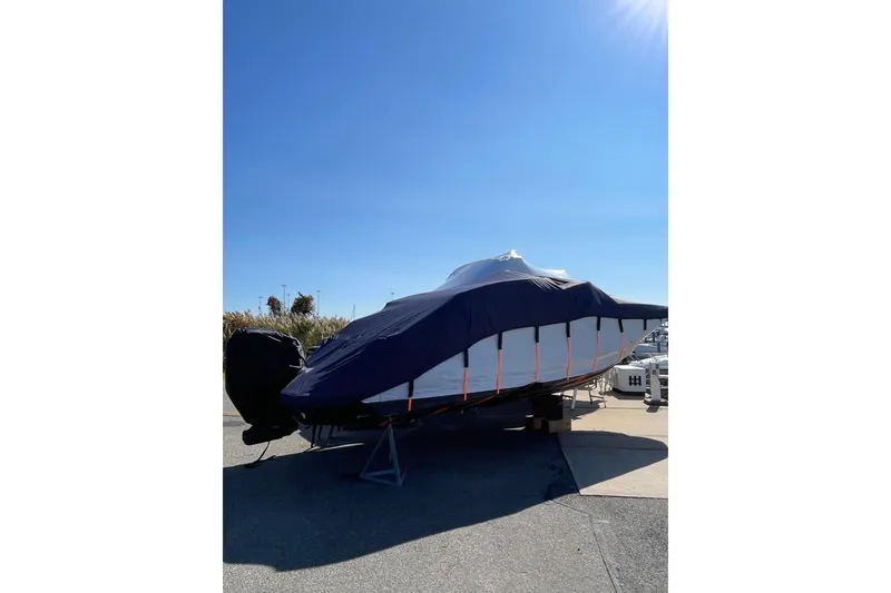 Slide: The Image of 2020 Regal 26 OBX boat covered and stored outdoors under a clear blue sky. - 26