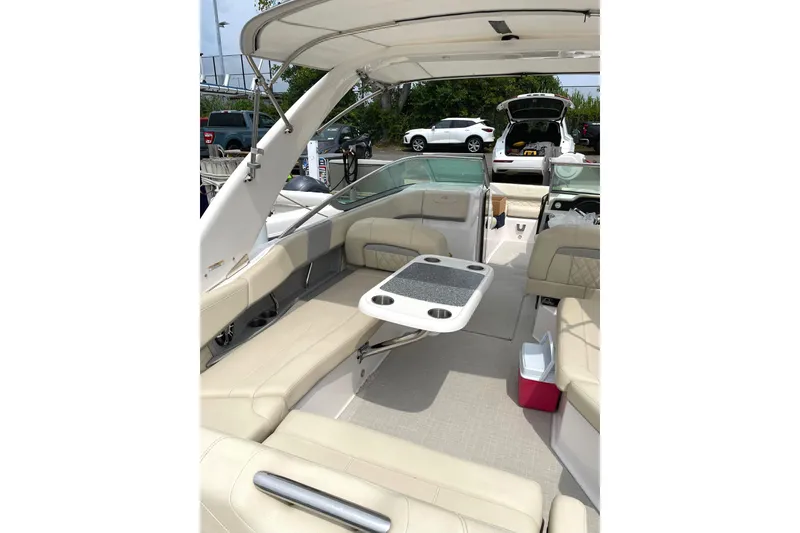 Slide: The Image of 2020 Regal 26 OBX boat interior with beige seating and table, parked outdoors. - 3