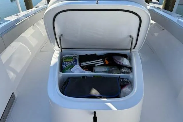 Slide: The Image of Open storage compartment on 2025 Front Runner 36 Center Console boat, filled with various items. - 8
