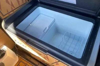 Slide: The Image of 2025 Tigé Ultré 25ZX boat cooler, open and empty, with storage compartments. - 10