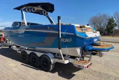 Slide: The Image of 2025 Tigé Ultré 25ZX boat on trailer, blue exterior, parked outdoors. - 3