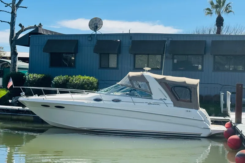 Slide: The Image of 2000 Sea Ray 290 Sundancer docked by a waterfront building under a clear blue sky. - 10