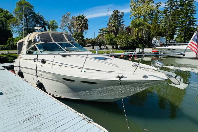 Slide: The Image of 2000 Sea Ray 290 Sundancer docked, featuring sleek design and American flag. - 11
