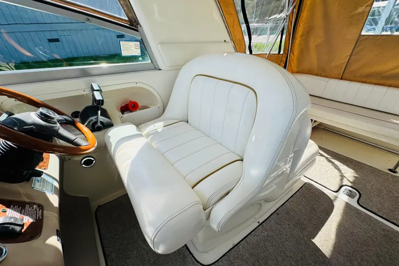 Slide: The Image of Captain's seat and helm of 2000 Sea Ray 290 Sundancer boat, featuring white upholstery. - 28