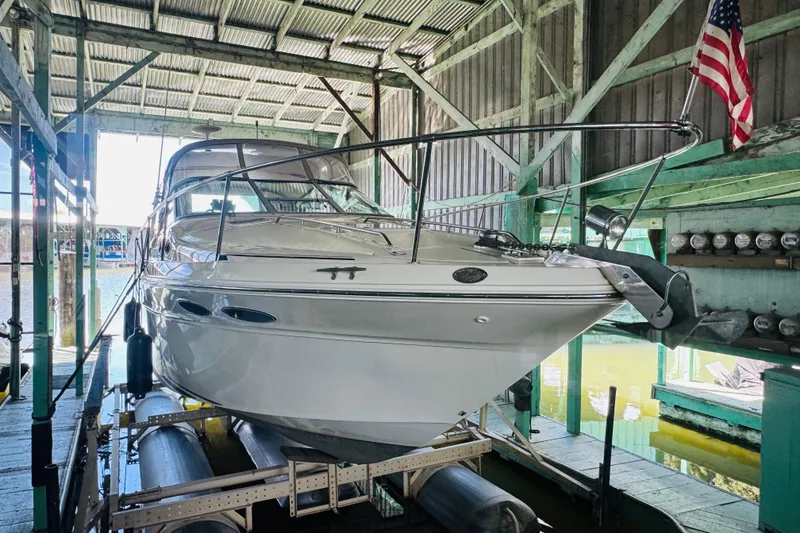 Slide: The Image of 2000 Sea Ray 290 Sundancer boat docked in a covered marina with American flag. - 6