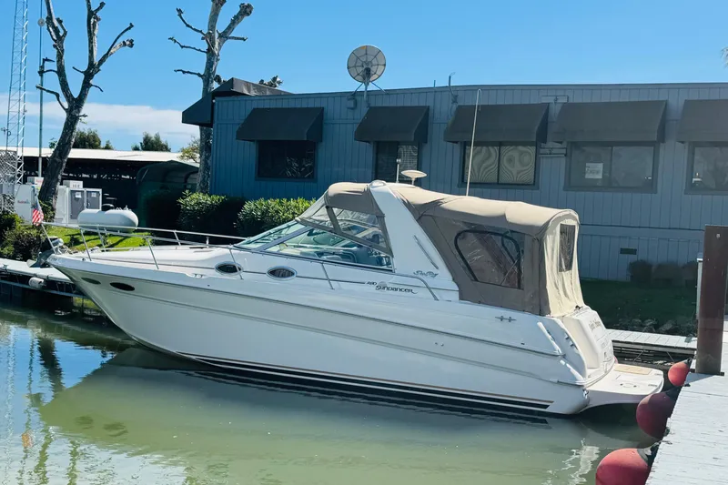 Slide: The Image of 2000 Sea Ray 290 Sundancer boat docked at marina, featuring beige canopy and sleek design. - 9