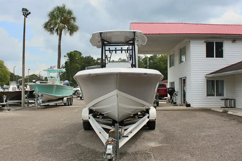 Slide: The Image of 2024 Clearwater 2300 CC boat on trailer, parked near a white building and palm tree. - 3