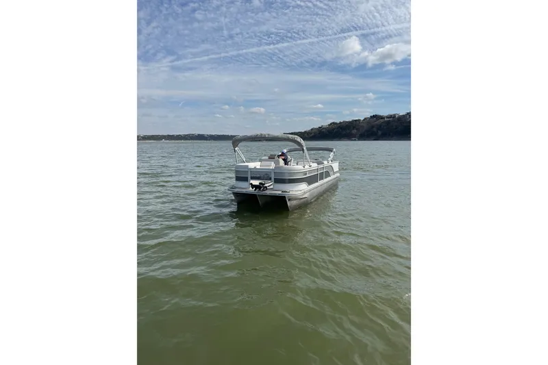 Slide: The Image of 2022 G3 Suncatcher Select 322RF pontoon boat on a calm lake under a blue sky. - 2