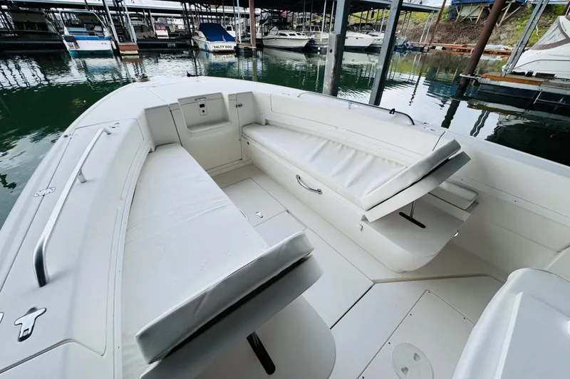 Slide: The Image of 2008 Intrepid 327 boat interior with white cushioned seating at a marina. - 21