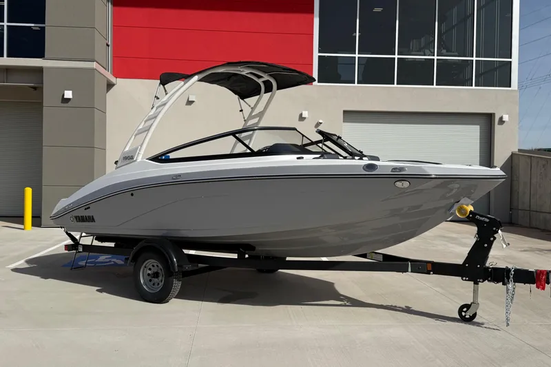 The Image of 2026 Yamaha Boats 195S on trailer, parked outside modern building. - 0