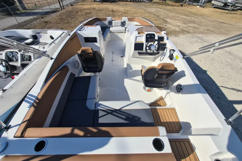 Slide: The Image of 2026 Starcraft SVX 231 OB DH boat interior with seating and steering wheel, parked outdoors. - 5