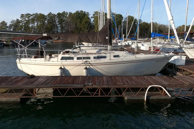 The Image of 1980 Catalina 30 sailboat docked, surrounded by trees. - 0