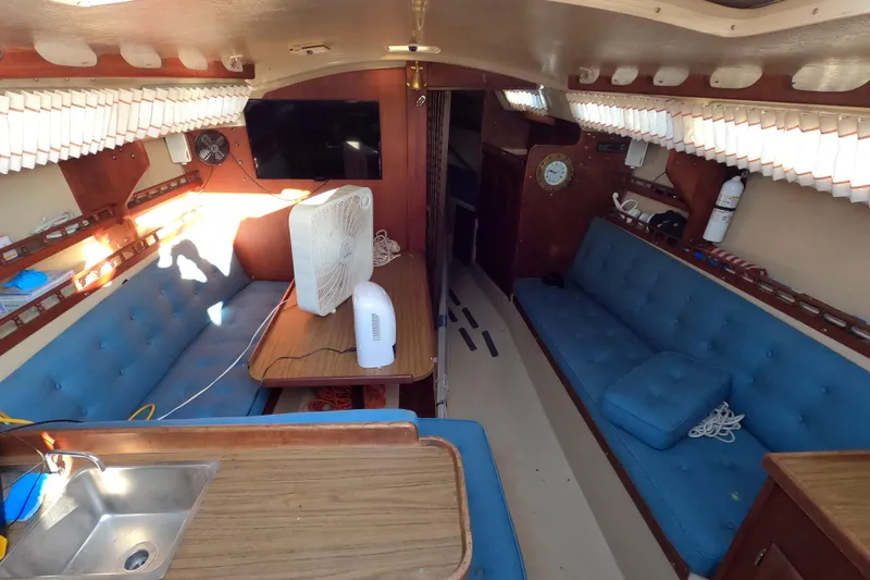 Slide: The Image of Interior of a 1980 Catalina 30 sailboat with blue seating and wooden accents. - 10