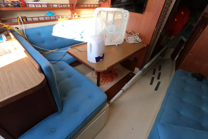 Slide: The Image of Interior of a 1980 Catalina 30 sailboat with blue seating and a fan on the table. - 11