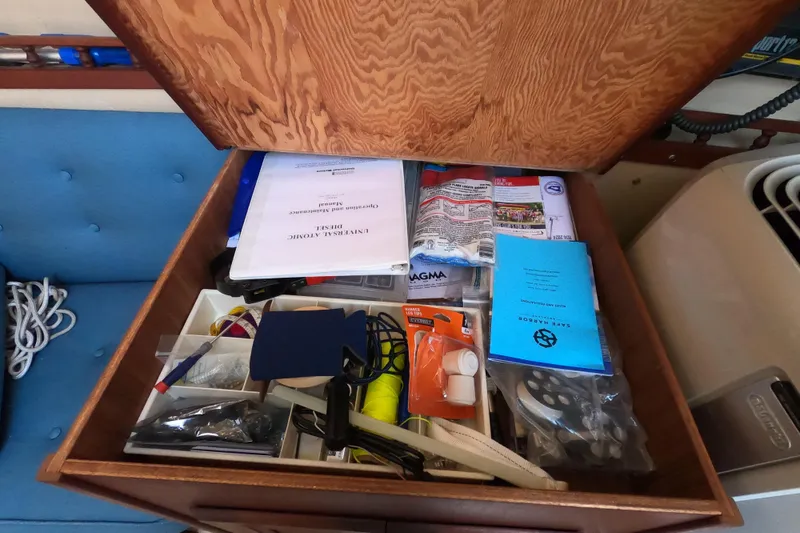 Slide: The Image of Storage compartment with manuals and tools on a 1980 Catalina 30 sailboat. - 17