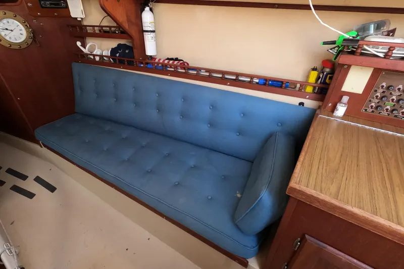 Slide: The Image of Interior of a 1980 Catalina 30 sailboat with blue cushioned seating and wooden cabinetry. - 18