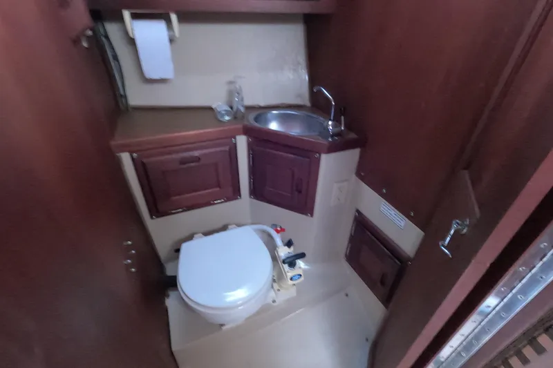 Slide: The Image of 1980 Catalina 30 sailboat bathroom with sink, toilet, and wooden cabinetry. - 19