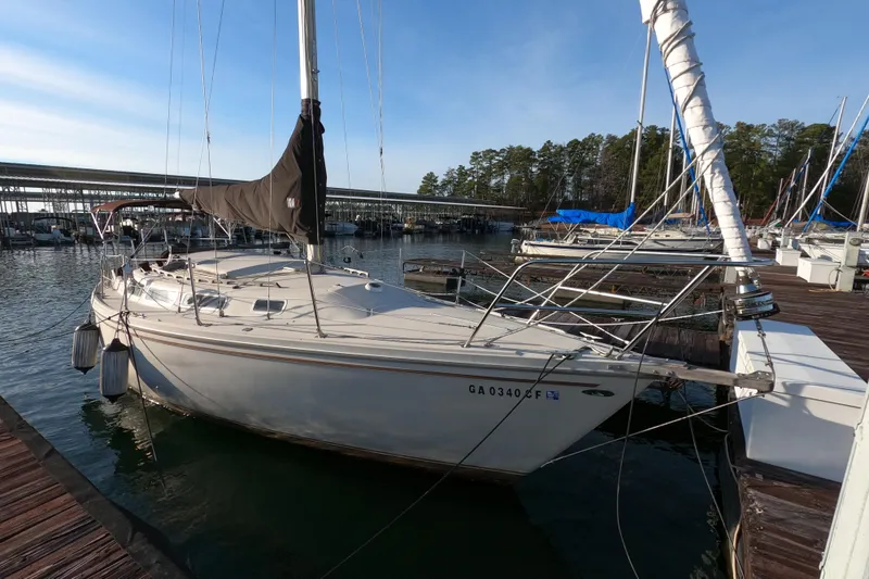 Slide: The Image of 1980 Catalina 30 sailboat docked at marina, surrounded by calm water and trees. - 2