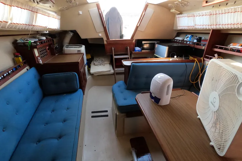 Slide: The Image of Interior of a 1980 Catalina 30 sailboat with blue seating and wooden table. - 24