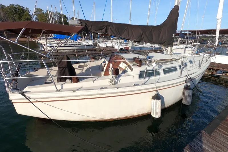 Slide: The Image of 1980 Catalina 30 sailboat docked at marina, featuring covered cockpit and fenders. - 3