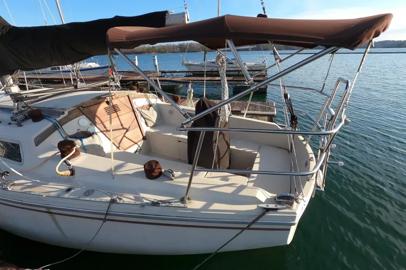 Slide: The Image of 1980 Catalina 30 sailboat docked, featuring a spacious cockpit and protective canopy. - 5