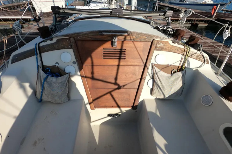 Slide: The Image of 1980 Catalina 30 sailboat cockpit with wooden hatch and storage pockets, docked at marina. - 6