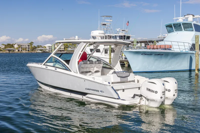 Slide: The Image of 2020 Chaparral 300 OSX boat with twin Yamaha engines docked in a marina. - 11