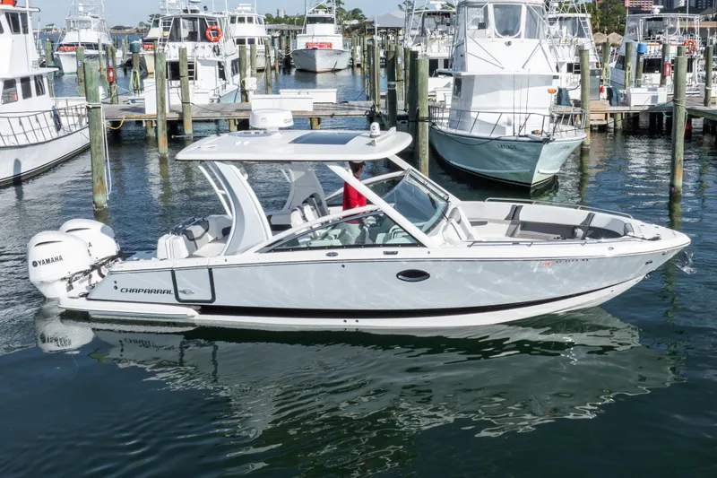 Slide: The Image of 2020 Chaparral 300 OSX boat docked in marina, featuring Yamaha engines. - 2